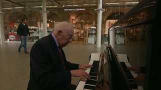 Denis Robinson playing the piano at London St Pancras station