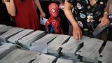 A child in a Spiderman costume stands next to a ballot table for the European Parliament election at a polling station in Madrid, Spain