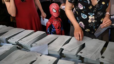 A child in a Spiderman costume stands next to a ballot table for the European Parliament election at a polling station in Madrid, Spain