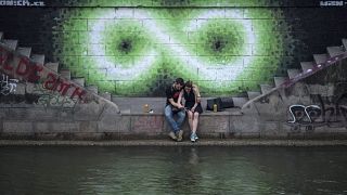 Egy pár ül a Duna partján Bécsben 2017 nyarán