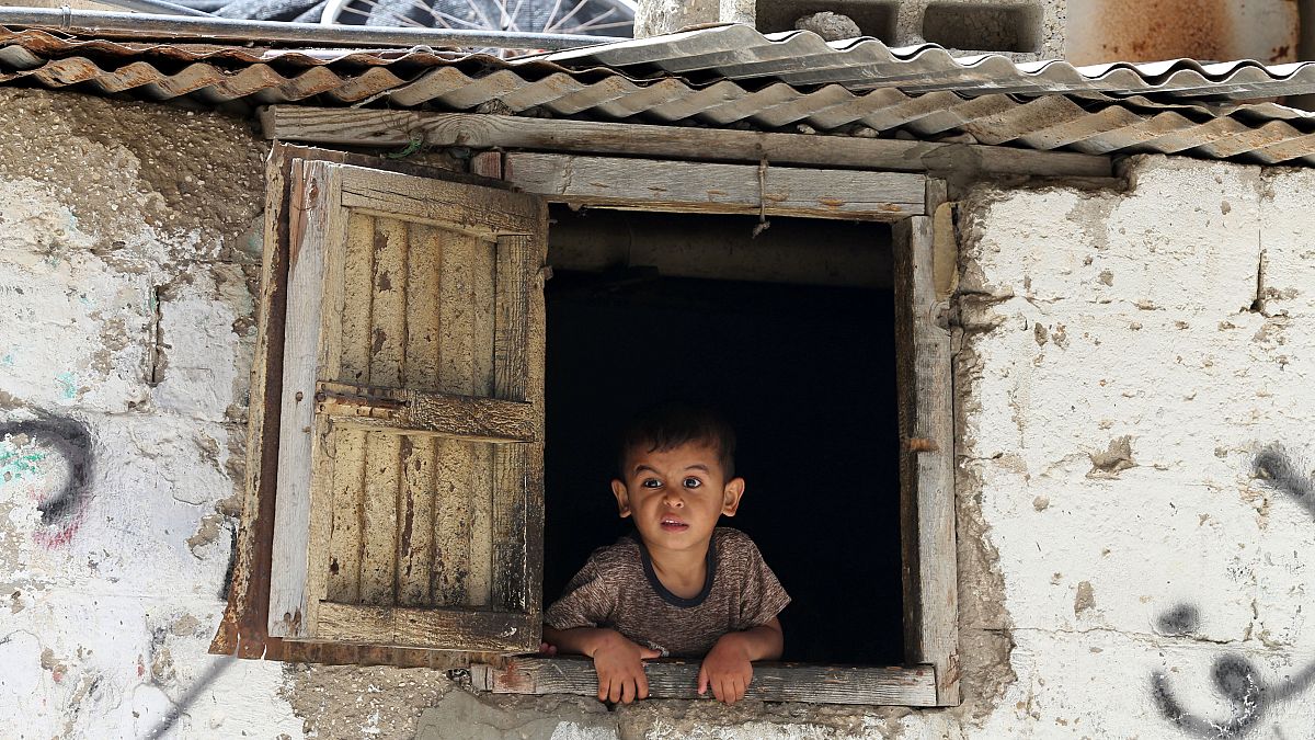 طفل فلسطيني ينظر من نافذة منزله في مخيم خان يونس جنوب غزة