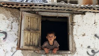 طفل فلسطيني ينظر من نافذة منزله في مخيم خان يونس جنوب غزة