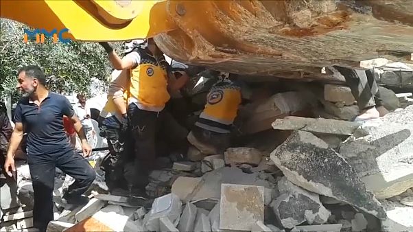 عناصر من القبعات البيضاء يتعاونون مع مدنيين لانتشال الفتى من تحت الأنقاض عناصر من القبعات البيضاء يتعاونون مع مدنيين لانتشال الفتى من تحت الأنقاض