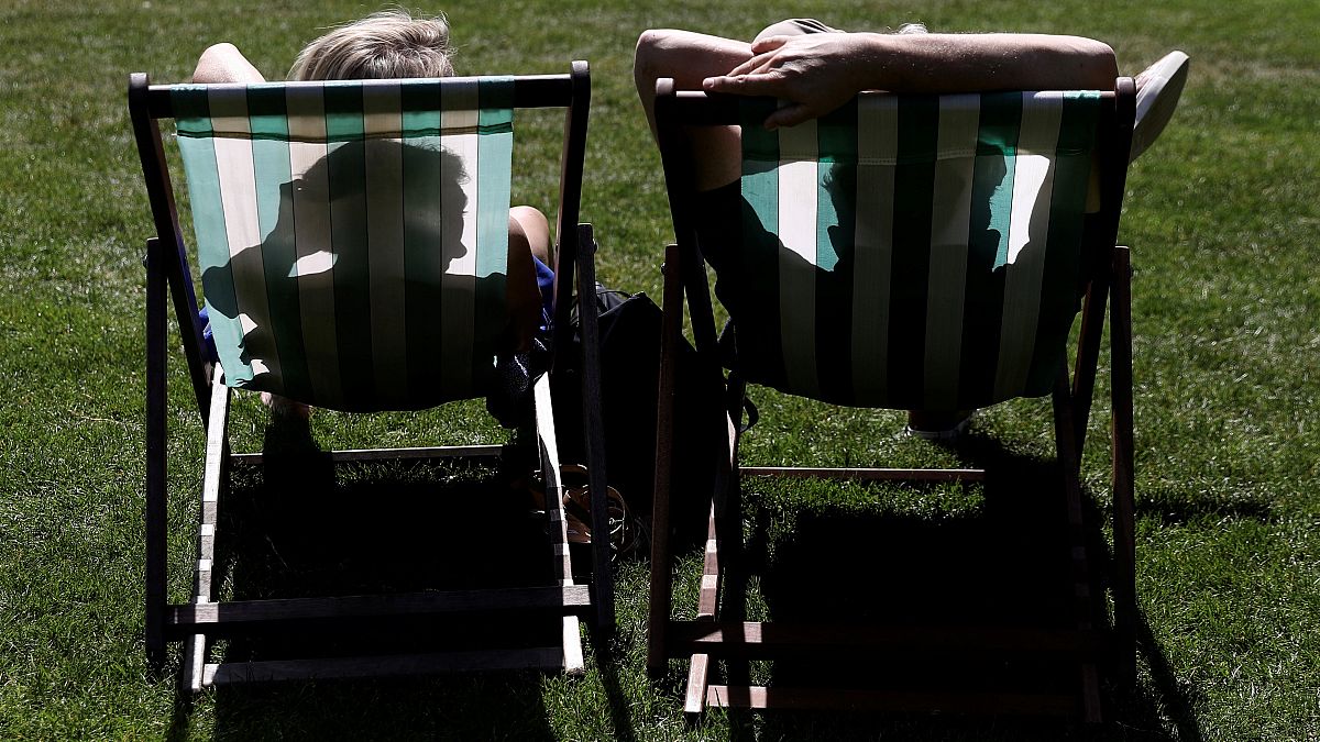People sit in St James’s Park during sunny weather in London, Britain