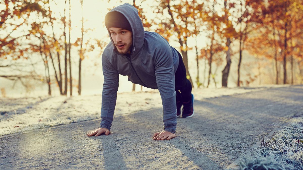 Young runner doing push ups exercise during cold autumn morning