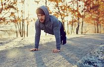 Young runner doing push ups exercise during cold autumn morning