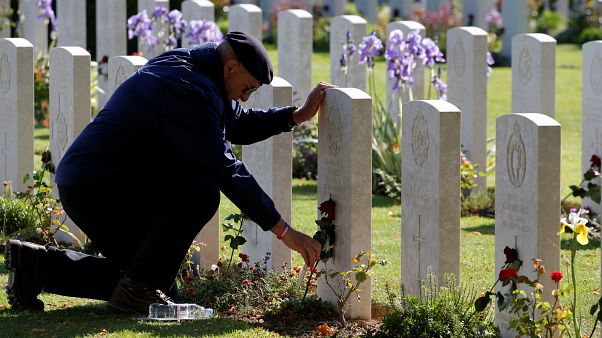A man places a flower on a tomb at Commonwealth War Cemetery in Bayeux A man places a flower on a tomb at Commonwealth War Cemetery in Bayeux