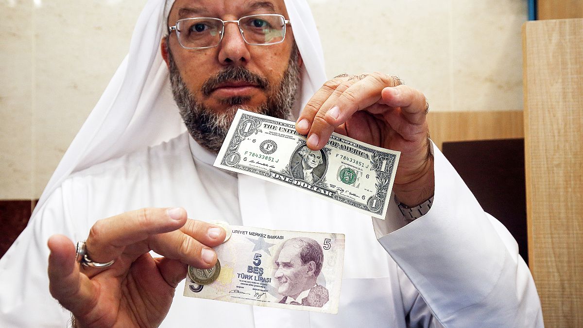 مواطن كويتي يحمل ورقة نقدية لدولار أميركي وأخرى لخمس ليرات تركية/آب-2018