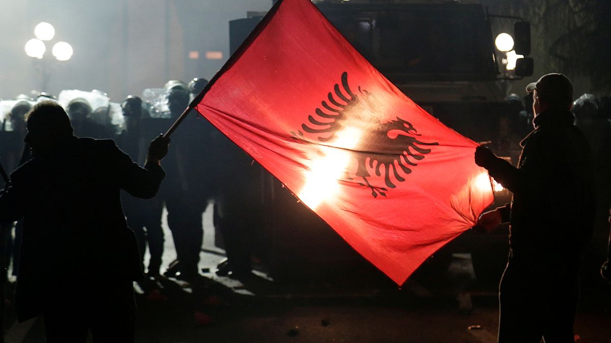 Anti-government supporters hold an Albanian flag in front of police during a protest in Tirana