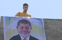 شاب يقوم بتعليق صورة كبيرة لرئيس مصر السابق محمد مرسي على حافة بناء في رفح بقطاع غزة
