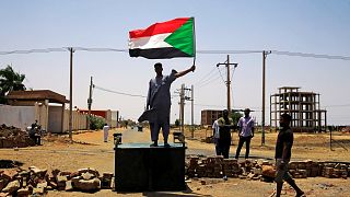 متظاهر سوداني يرفع العلم الوطني في الخرطوم يوم 5 يونيو حزيران 2019