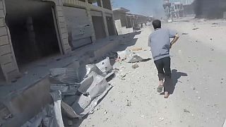 أحد المدنيين يركض قرب بلدة معرة النعمان بعد قصف جوي عنيف للإنقاذ أو العثور على الضحايا