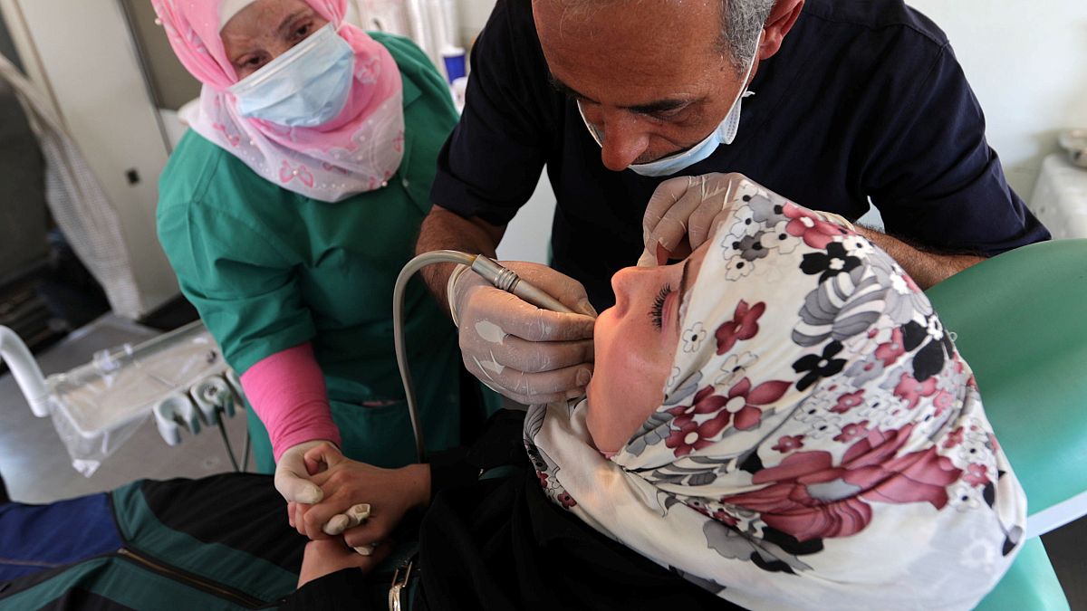 طبيب الأسنان باسل معراوي يعتني بمريضة في عيادة متنقلة في شاحنة بالقرب من أعزاز 
