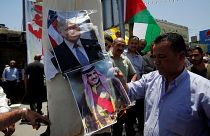 A Palestinian demonstrator burns posters depicting Bahrain's King Hamad bin Isa Al Khalifa and U.S. President Donald Trump during a protest against the Bahrain conference