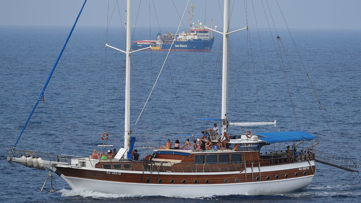 Veleiro com turistas a navegar ao largo de Lampedusa não muito longe do barco de socorro a migrantes
