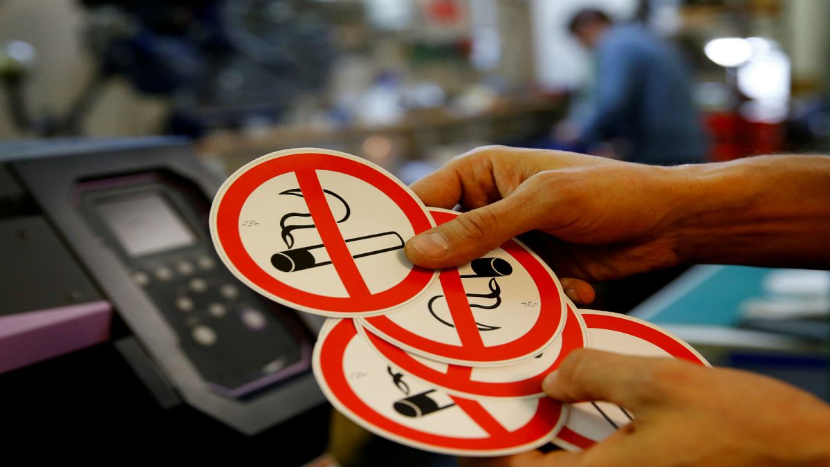 موظف يُظهر لافتات "ممنوع التدخين" في ورشة الطباعة في فيينا/ النمسا 2018