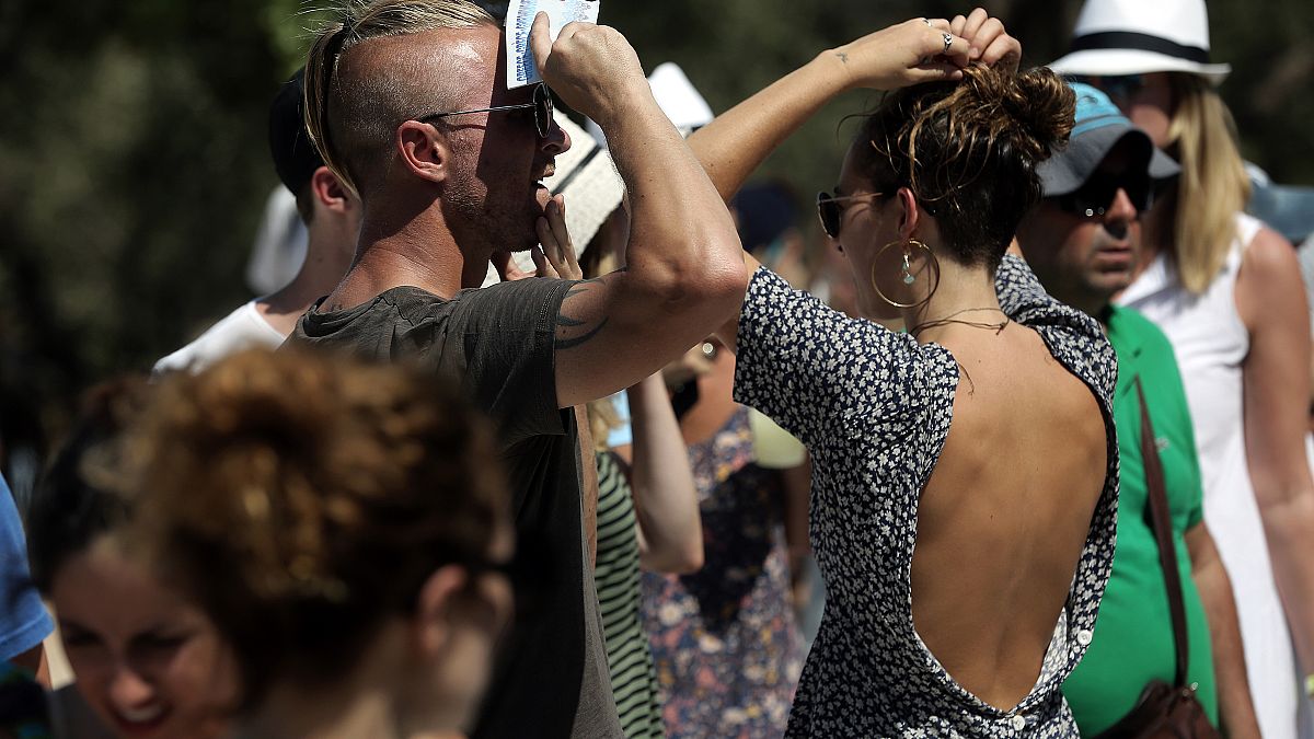 Τουρίστες προσπαθούν να προστατευθούν από το δυνατό ήλιο της Αθήνας