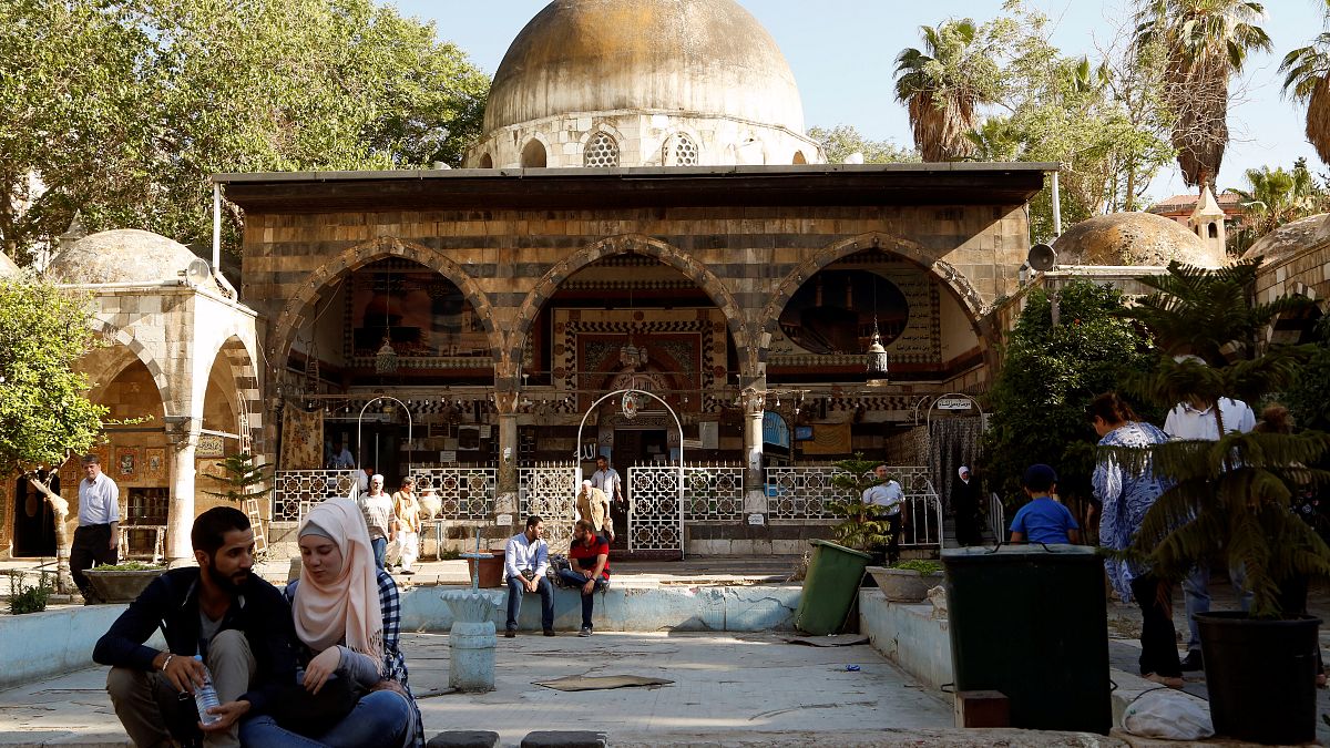People sit near the Ottoman-era Tekkiye Suleimaniye mosque complex in Damascus, Syria