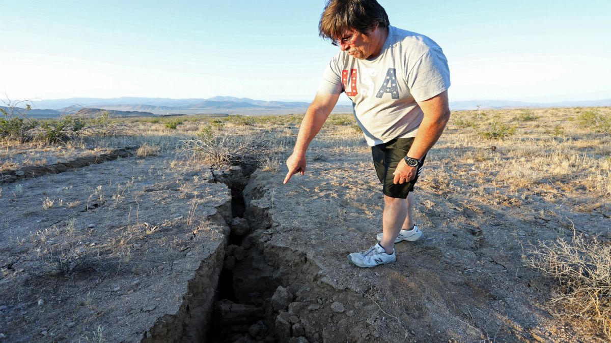 رجل يشير إلى أخدود في الأرض أحدث جراء زلزال جنوبي كاليفورنيا