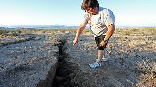 رجل يشير إلى أخدود في الأرض أحدث جراء زلزال جنوبي كاليفورنيا