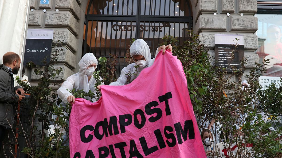 Klimaaktivisten halten ein Banner: "Compost Capitalism"