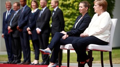 Merkel assiste a hinos sentada 