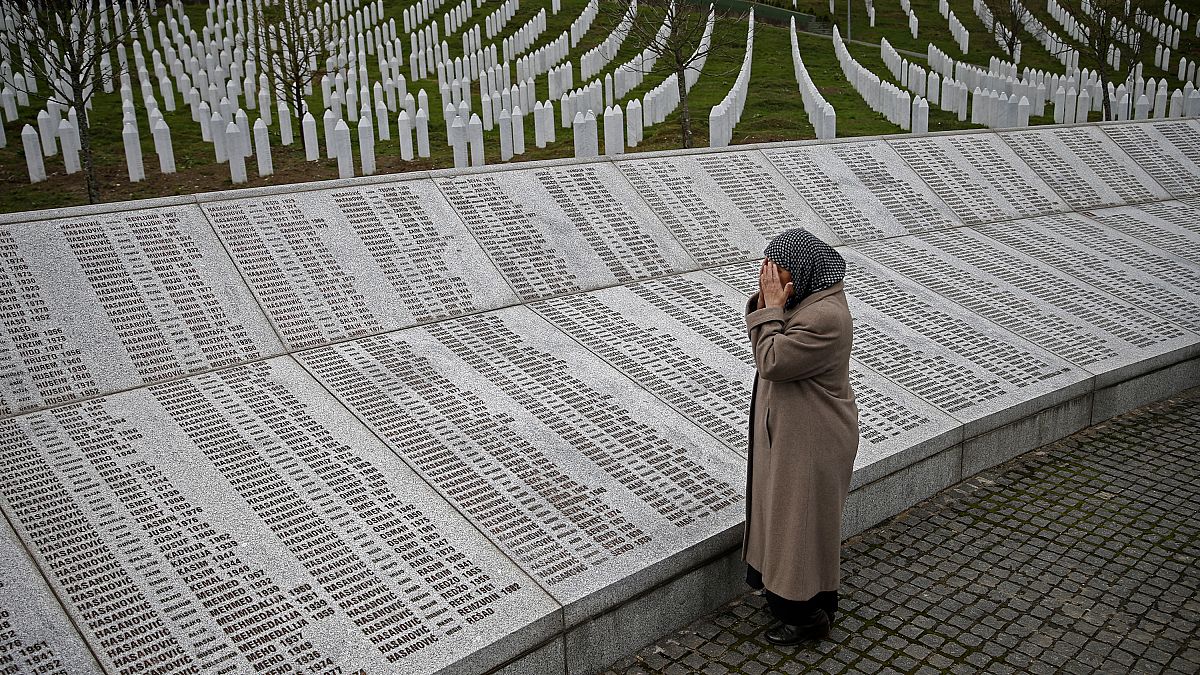 Una mujer reza cerca de la placa conmemorativa con nombres de fallecidos en la masacre de Srebrenica, antes de ver el juicio en el tribunal de La Haya, en Potocari.