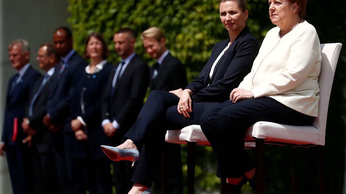 في مخالفة للبروتوكول، جلست ميركل بجانب رئيسة وزراء الدنمارك، ميتيه فريدريكسن، خلال تأدية النشيدين الوطنييْن