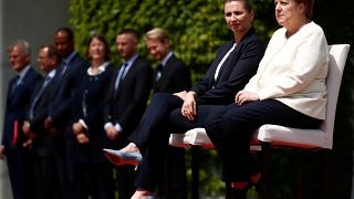 في مخالفة للبروتوكول، جلست ميركل بجانب رئيسة وزراء الدنمارك، ميتيه فريدريكسن، خلال تأدية النشيدين الوطنييْن