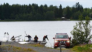 An emergency services boat carrying wreckage parts arrives at a harbour near the site