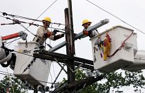 عاملان يصلحان أحد خطوط الكهرباء التي تضررت بفعل العاصفة باري في نيو أورليانز بولاية لويزيانا الأمريكية يوم الاحد
