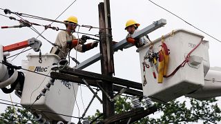 عاملان يصلحان أحد خطوط الكهرباء التي تضررت بفعل العاصفة باري في نيو أورليانز بولاية لويزيانا الأمريكية يوم الاحد