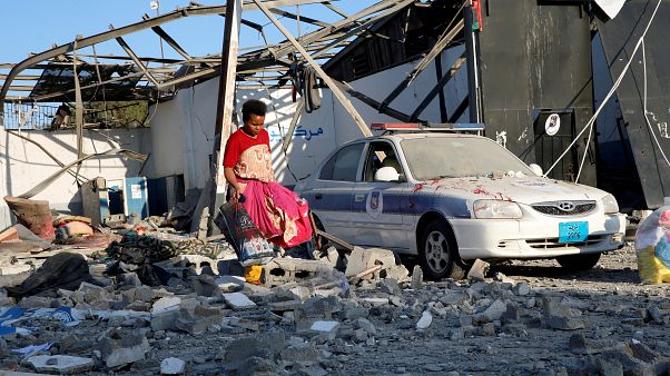 A Tripoli melletti lebombázott menekülttáborban gyűjt ruhákat egy migráns A Tripoli melletti lebombázott menekülttáborban gyűjt ruhákat egy migráns