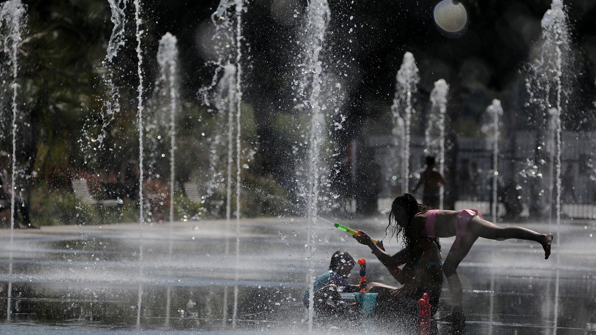 FILE PHOTO: People cool off in a fountain in Nice as a heatwave hits much of the country, France