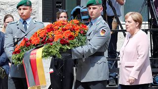 Angela Merkel stands with German soldiers laying a wreath to honour the failed plotters