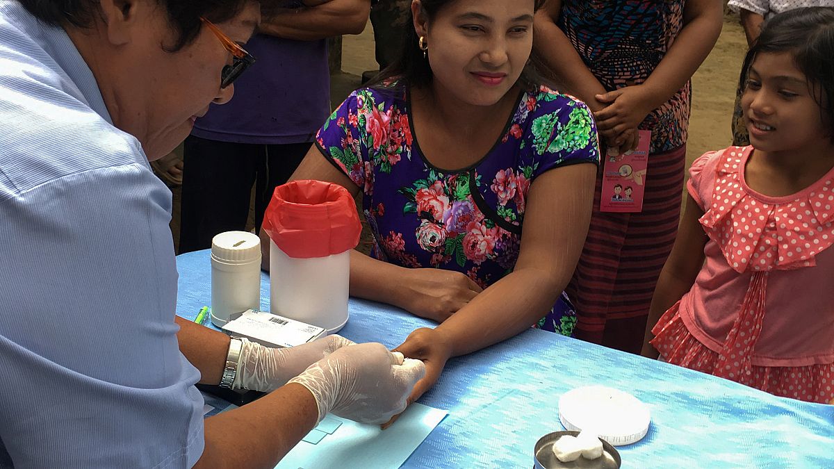 موظف في مجال الصحة في تايلاند يسحب عينة من امرأة لفحص الملاريا