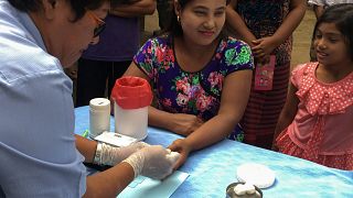 موظف في مجال الصحة في تايلاند يسحب عينة من امرأة لفحص الملاريا