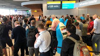 Passengers and staff wait at Amsterdam Schiphol airport during an outage at the airport's main fuel supplier that kept dozens of flights on the ground, 