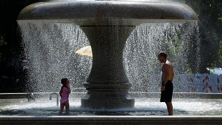 A man and a child cool off in a fountain on a hot summer day in Frankfurt