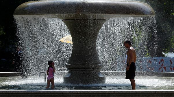 A man and a child cool off in a fountain on a hot summer day in Frankfurt A man and a child cool off in a fountain on a hot summer day in Frankfurt