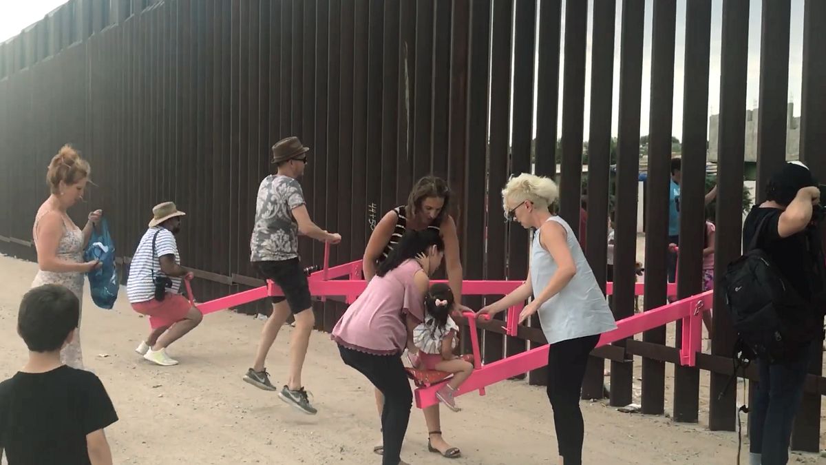 People play on a set of fluorescent pink seesaws across the US-Mexico border in Sunland Park, New Mexico, US