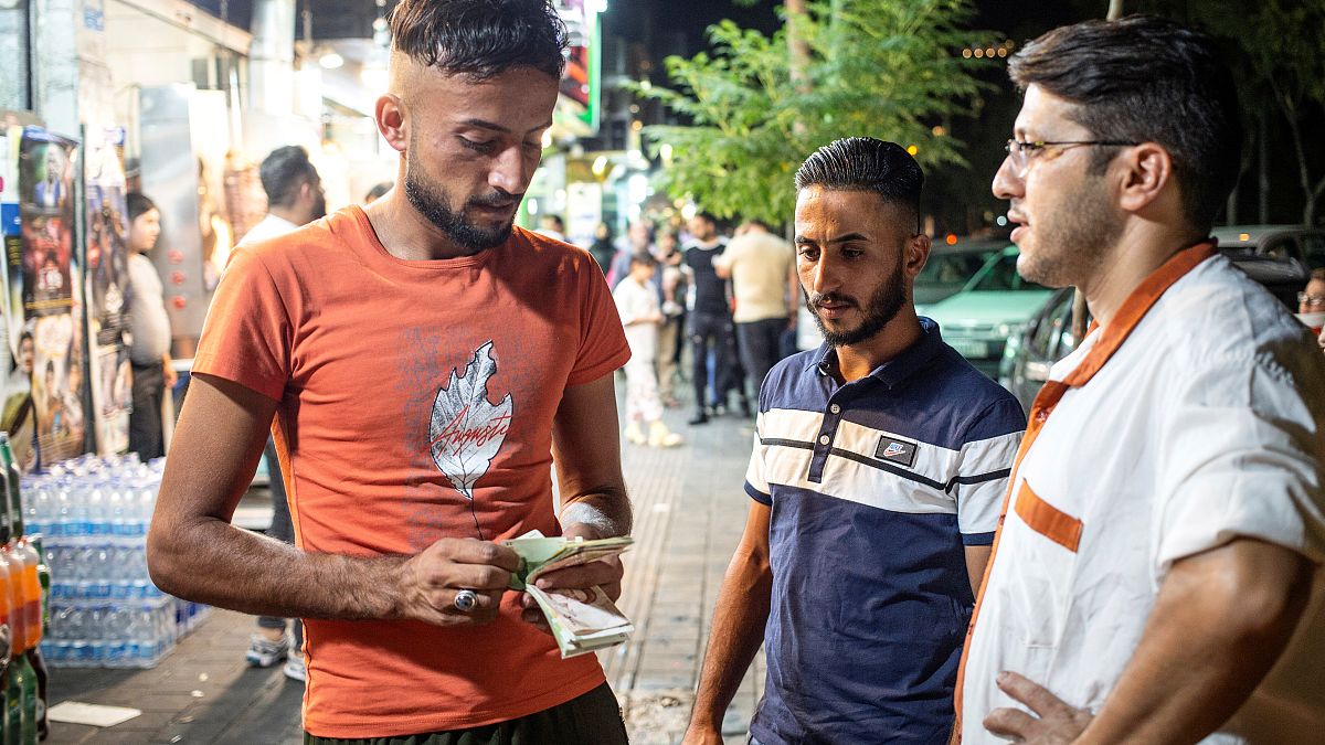رجل عراقي يحسب المال على الرصيف في حي دولتاباد في طهران، إيران 19 تموز/يوليو 2019