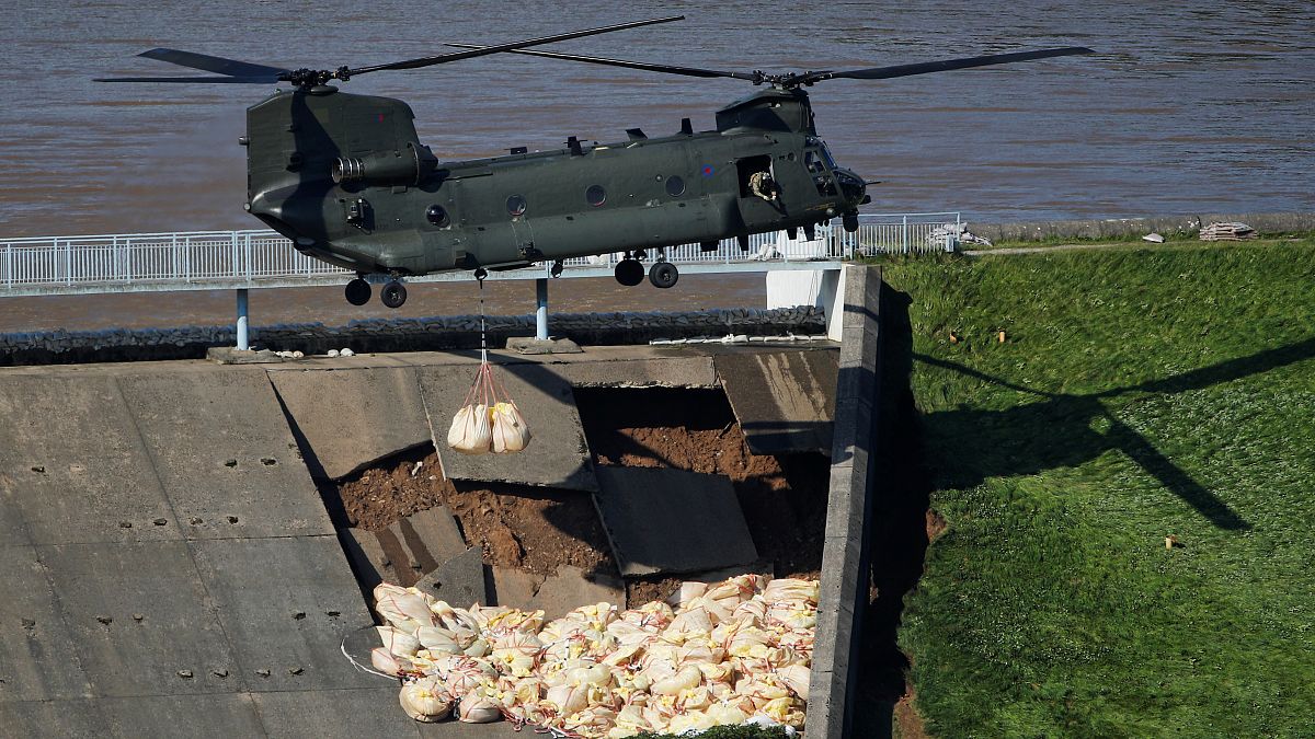 طائرة هليكوبتر عسكرية بريطانية تلقي أكياسا من الحصى على منحدر خارجي لسد انهار جزء منه وبات معرضا لخطر الانهيار وإغراق بلدة وايلي بريدج في منطقة ديربيشاير 