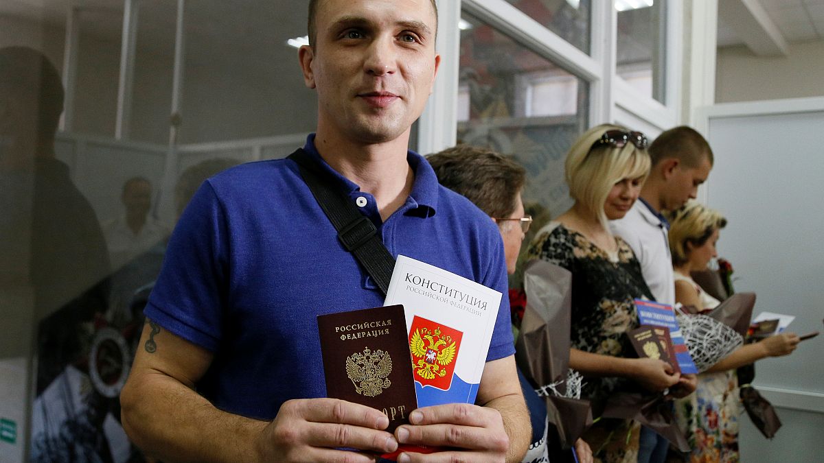 Un residente de la autoproclamada República Popular de Donetsk sostiene su pasaporte ruso y una copia de la Constitución de Rusia