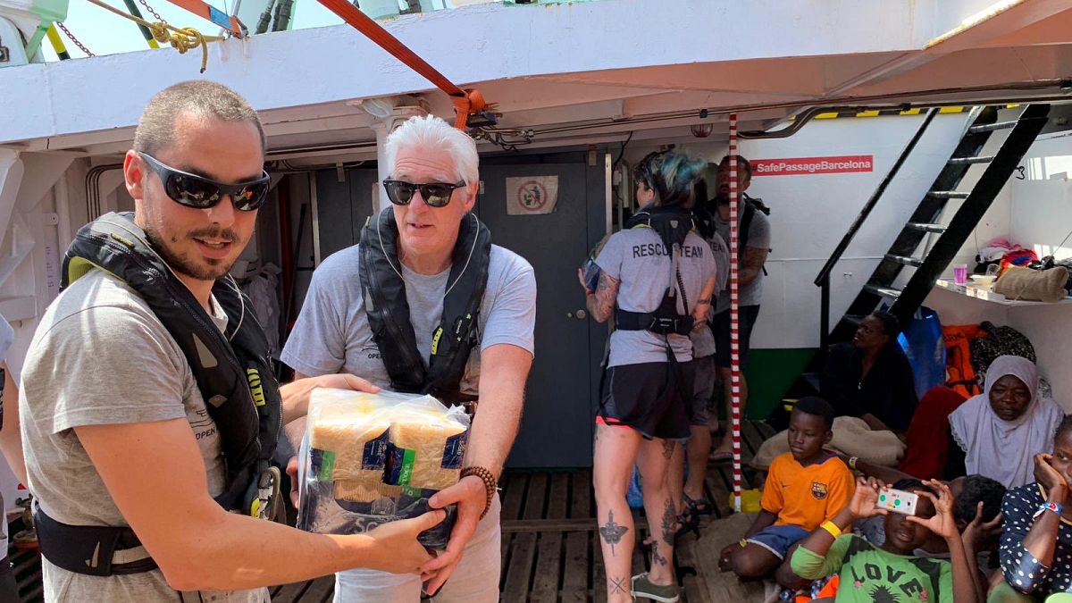 U.S. actor Richard Gere helps to carry supplies aboard the Open Arms rescue boat