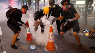  Des manifestants tentent d'éteindre des cartouches de gaz lacrymogène lors d'une manifestation dans le quartier de Wan Chai à Hong Kong