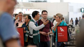 مسافرون يتحدثون مع أحد موظفي مطار هونغ كونغ يوم الثلاثاء