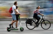 Radfahrerin überholt in Berlin zwei Verkehrsteilnehmer auf einem E-Tretroller.