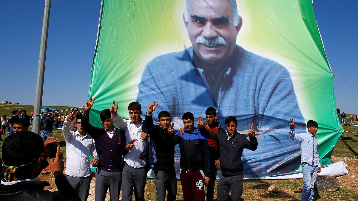 Kurdish men pose for a picture in front of the portrait of jailed Kurdish militant leader Abdullah Ocalan