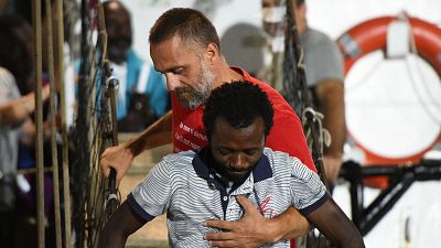 Un migrant aidé à descendre du navire humanitaire Open Arms